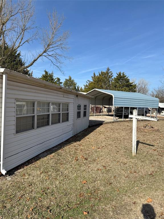 view of side of property with a carport and a lawn