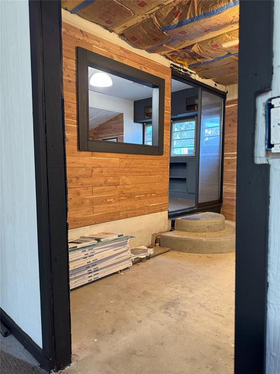 hallway featuring wooden walls and concrete floors