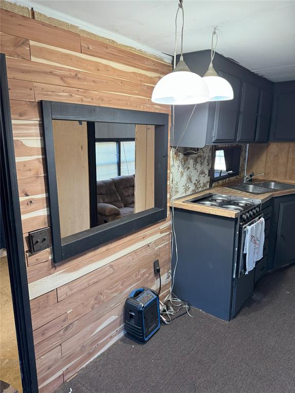 kitchen with decorative light fixtures, black electric range oven, and wooden walls