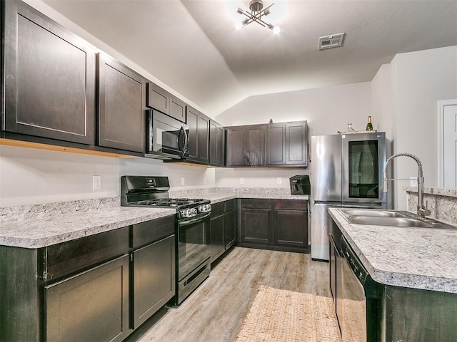 kitchen with sink, vaulted ceiling, light wood-type flooring, appliances with stainless steel finishes, and dark brown cabinetry