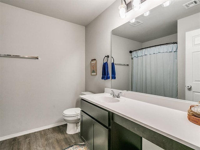 bathroom featuring walk in shower, vanity, wood-type flooring, and toilet