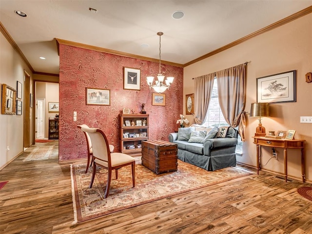 living area with hardwood / wood-style flooring, ornamental molding, and an inviting chandelier