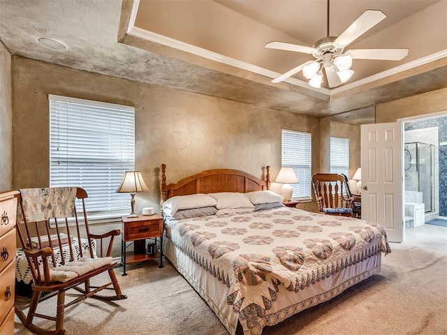 carpeted bedroom with crown molding and a tray ceiling