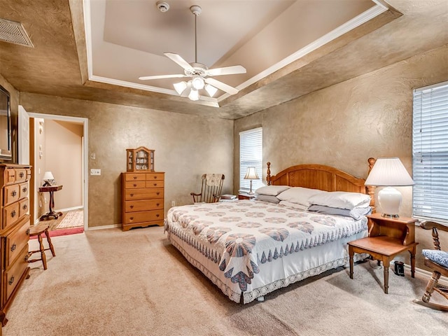 carpeted bedroom with a raised ceiling and ceiling fan