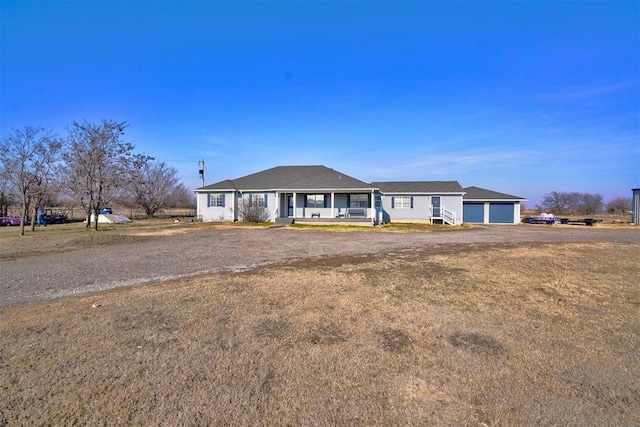 ranch-style house with covered porch, an outdoor structure, and a garage