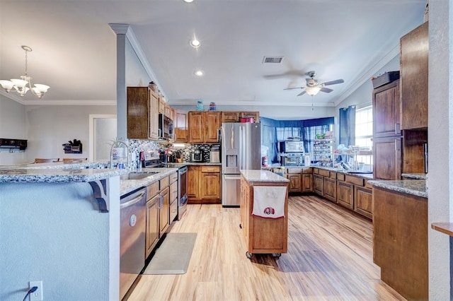 kitchen featuring stainless steel appliances, a kitchen breakfast bar, kitchen peninsula, decorative light fixtures, and ornamental molding