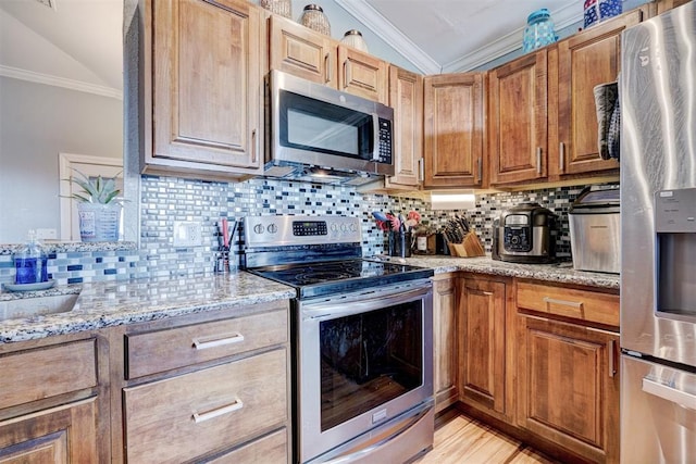 kitchen featuring light stone countertops, lofted ceiling, crown molding, and appliances with stainless steel finishes