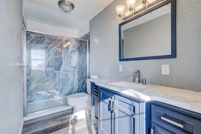 bathroom featuring vanity, hardwood / wood-style flooring, toilet, and a shower with door