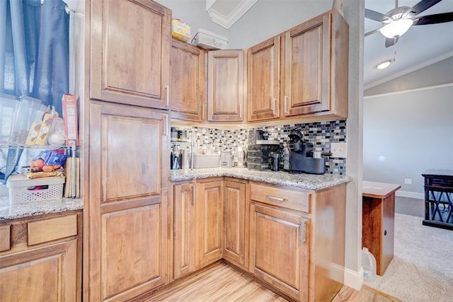 kitchen with decorative backsplash, light hardwood / wood-style floors, vaulted ceiling, and light stone countertops