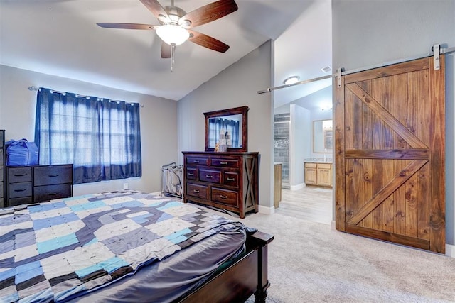 carpeted bedroom featuring connected bathroom, a barn door, ceiling fan, and vaulted ceiling