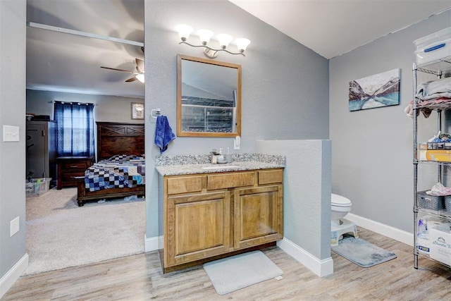 bathroom featuring ceiling fan, toilet, vanity, and hardwood / wood-style flooring