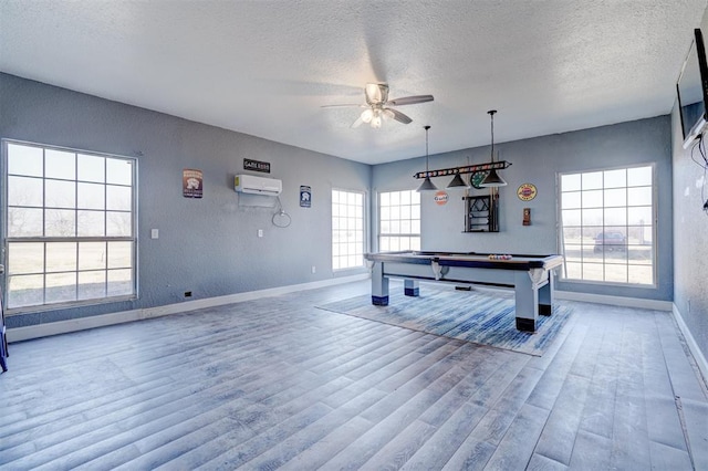 playroom with ceiling fan, billiards, an AC wall unit, hardwood / wood-style floors, and a textured ceiling