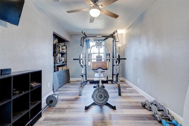 workout room with ceiling fan and light hardwood / wood-style flooring