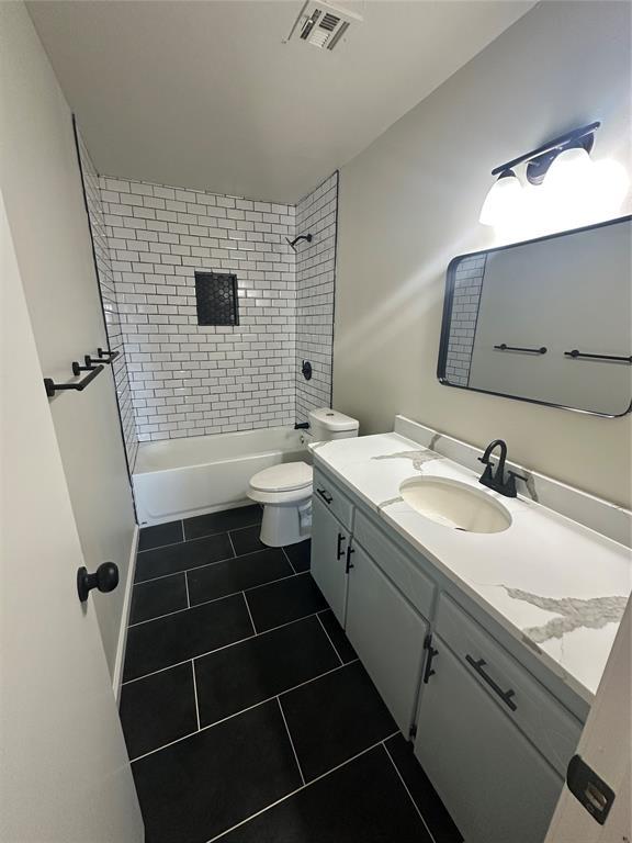 full bathroom featuring toilet, tiled shower / bath, tile patterned floors, and vanity