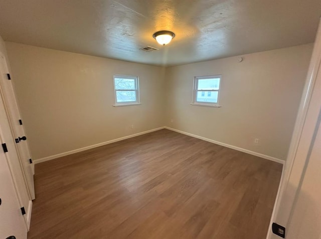 spare room with a wealth of natural light and dark hardwood / wood-style floors