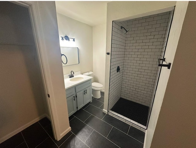 bathroom with tile patterned floors, vanity, a tile shower, and toilet