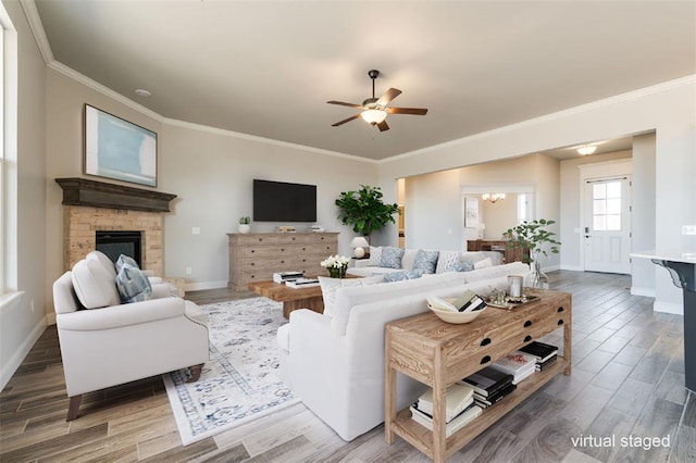 living room with hardwood / wood-style flooring, crown molding, a brick fireplace, and ceiling fan with notable chandelier