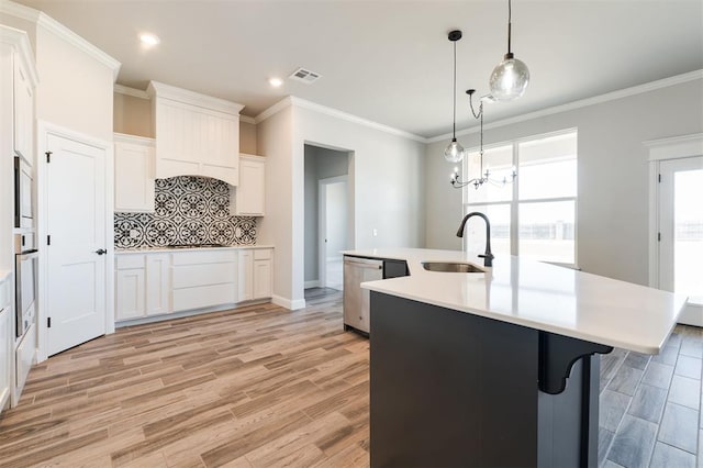 kitchen with pendant lighting, sink, white cabinetry, a center island with sink, and a chandelier