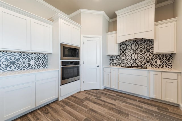 kitchen with appliances with stainless steel finishes, white cabinets, light countertops, and ornamental molding