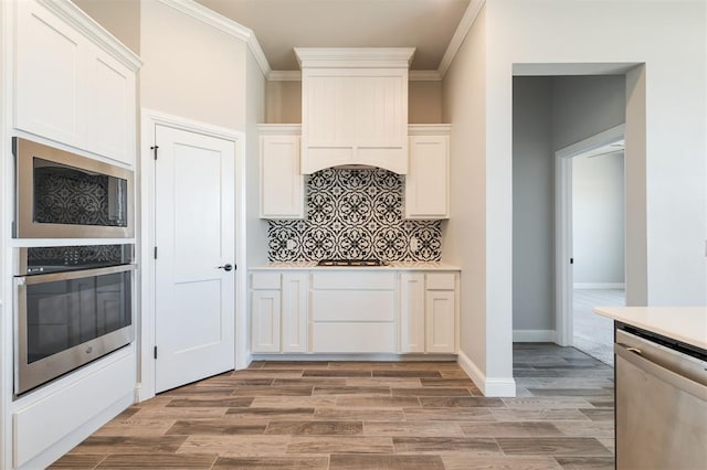 kitchen with stainless steel appliances, ornamental molding, and white cabinets