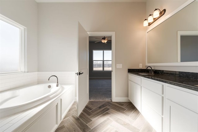 bathroom with ceiling fan, vanity, and a bath