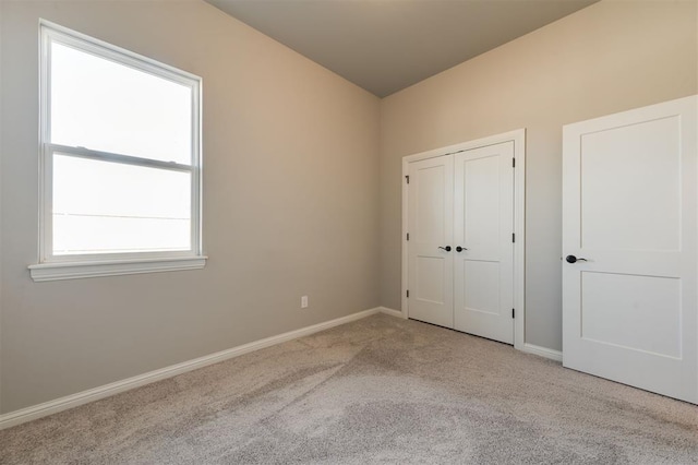 unfurnished bedroom featuring light carpet and a closet