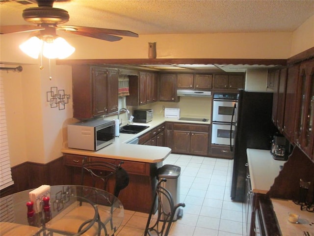 kitchen featuring ceiling fan, sink, kitchen peninsula, light tile patterned flooring, and black appliances