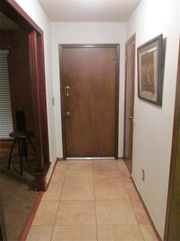 corridor featuring light tile patterned floors and a textured ceiling