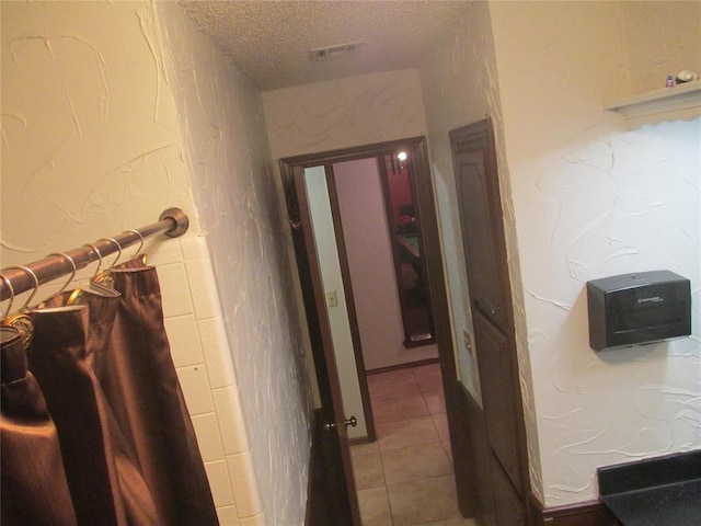 hallway featuring tile patterned floors and a textured ceiling