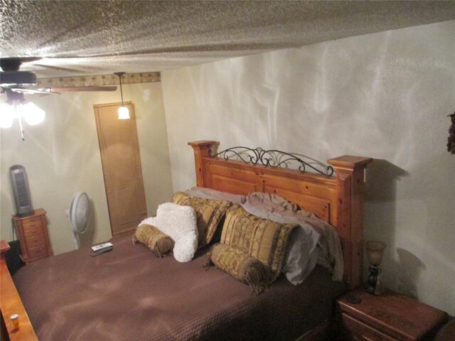 carpeted bedroom with ceiling fan and a textured ceiling