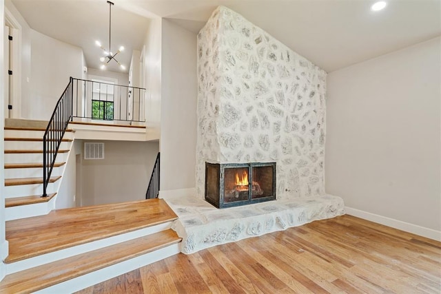 unfurnished living room featuring an inviting chandelier, a large fireplace, and wood-type flooring