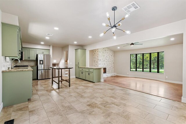 interior space with a stone fireplace, sink, and ceiling fan with notable chandelier