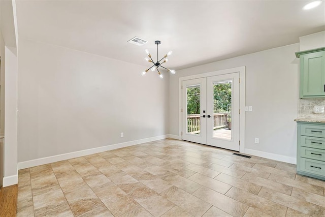 spare room with french doors and a notable chandelier