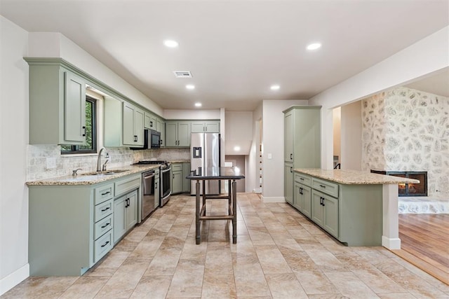 kitchen featuring light stone countertops, sink, stainless steel appliances, and green cabinets