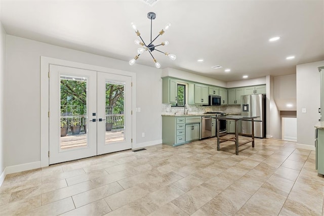 kitchen with appliances with stainless steel finishes, french doors, tasteful backsplash, light stone counters, and green cabinets