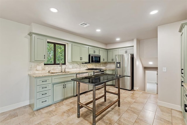 kitchen with stainless steel appliances, light stone counters, tasteful backsplash, and sink