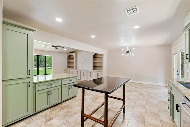 kitchen featuring green cabinets, built in shelves, ceiling fan with notable chandelier, and light stone countertops