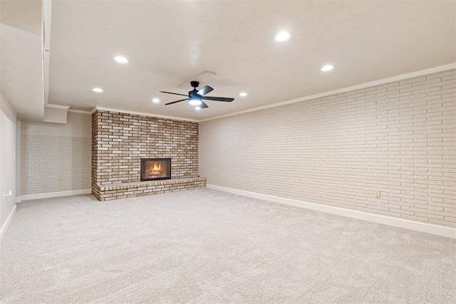 unfurnished living room featuring carpet floors, ceiling fan, a fireplace, crown molding, and brick wall