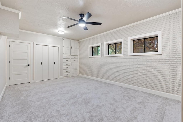 unfurnished bedroom featuring ceiling fan, light colored carpet, brick wall, and ornamental molding