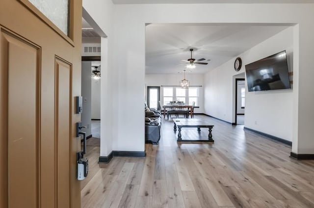 living room featuring light wood-type flooring and ceiling fan with notable chandelier