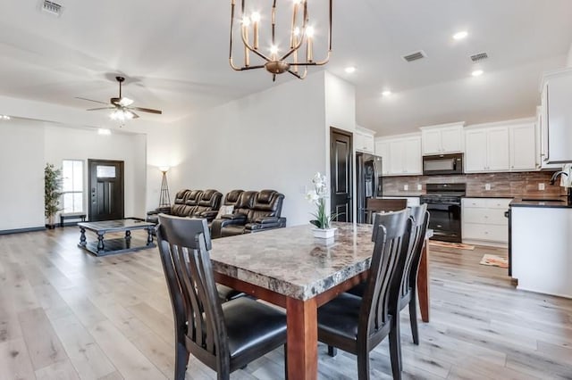 dining space featuring ceiling fan with notable chandelier, light hardwood / wood-style flooring, and sink