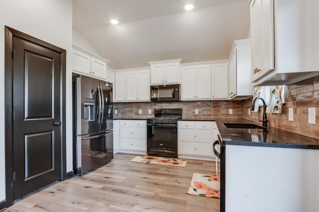 kitchen featuring white cabinetry, sink, lofted ceiling, decorative backsplash, and black appliances