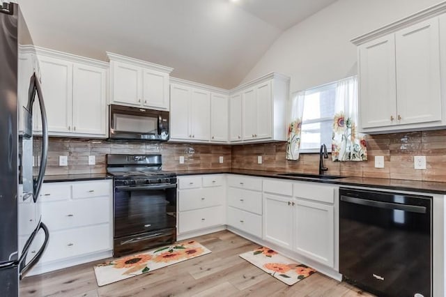 kitchen featuring backsplash, sink, white cabinets, and black appliances