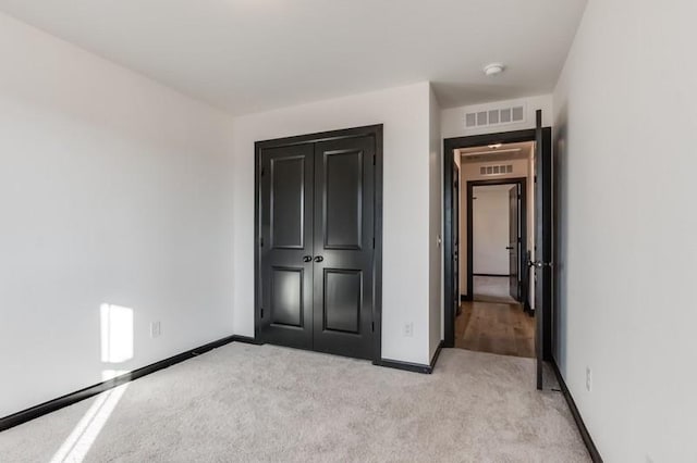 unfurnished bedroom with light carpet and a closet