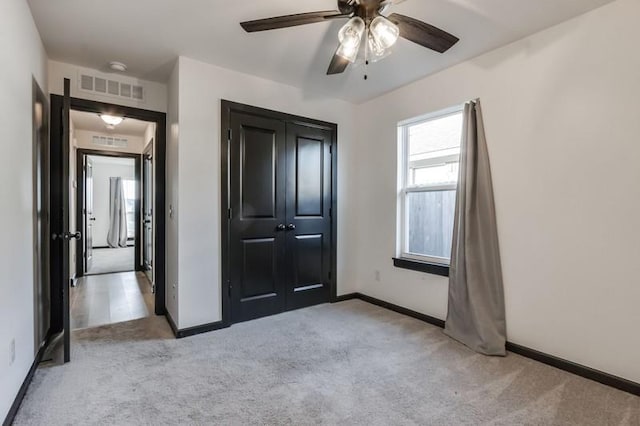 unfurnished bedroom with a closet, light colored carpet, and ceiling fan