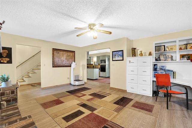 home office featuring a textured ceiling, ceiling fan, and light hardwood / wood-style flooring