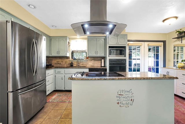 kitchen with light tile patterned flooring, sink, island range hood, black appliances, and backsplash