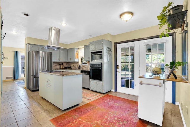 kitchen with island range hood, stainless steel appliances, decorative backsplash, and a kitchen island