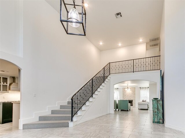 staircase with a high ceiling and a notable chandelier