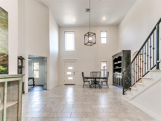 tiled foyer entrance featuring a chandelier and a high ceiling